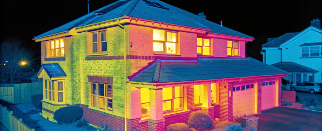 Home energy audit cost: thermal camera view of a house showing heat escaping around the windows and roofline